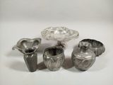 a group of silver vases sitting on a white surface