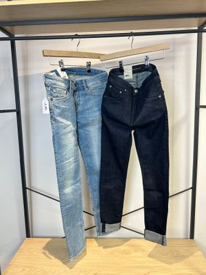 deux paires de jeans suspendues à un portant dans un magasin de vêtements