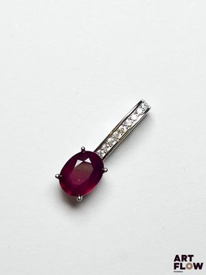 un gros plan d'un pendentif en rubis et diamants posé sur une surface blanche