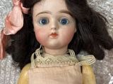 a close up of a doll with a pink bow on it ' s head