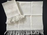 deux serviettes blanches à franges posées sur une surface noire