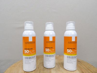three bottles of sunscreen lotion sitting on a wooden table