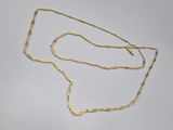 a gold necklace with a long chain on a white surface