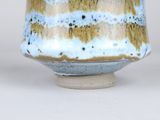 a close up of a blue and brown vase on a white surface