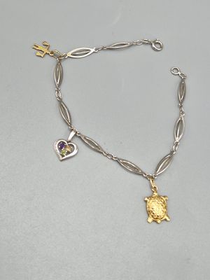 un gros plan sur un bracelet en argent orné d'une breloque dorée et violette