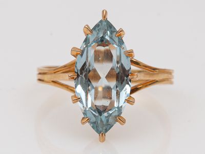Gros plan sur une bague en or ornée d'une topaze bleue