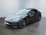 une Tesla Model 3 noire garée dans une pièce blanche