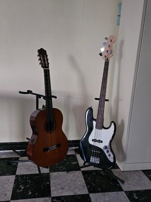 two guitars sitting on a stand in the corner of a room