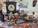 de nombreuses figurines posées sur une table, avec une horloge en arrière-plan