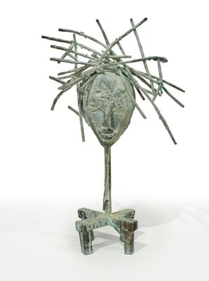 sculpture représentant une tête, réalisée à partir de bâtons et de brindilles, posée sur un socle