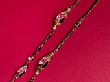 a long necklace with pink and gold beads on a pink background