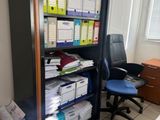un bureau avec une chaise et une bibliothèque remplie de papiers
