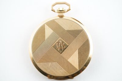 une montre de poche en or sur une surface blanche