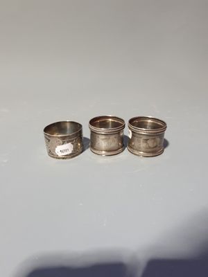 three silver napkin rings sitting on top of a white table