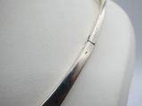 silver plated necklace with a curved design on a mannequin neck