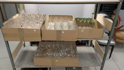 Des cartons contenant des verres à vin vides sont empilés sur un chariot dans une pièce