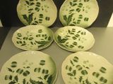 six assiettes vertes et blanches ornées de motifs, posées sur une table