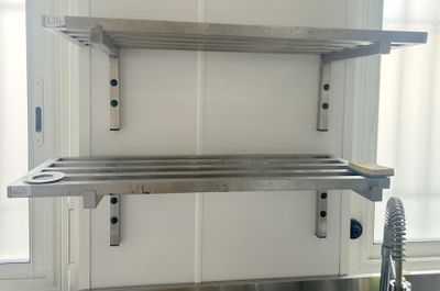 une photo d'une étagère en acier inoxydable au-dessus d'un évier de cuisine