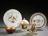Plusieurs assiettes et bols sont posés sur une table, sur laquelle se trouve un oiseau.