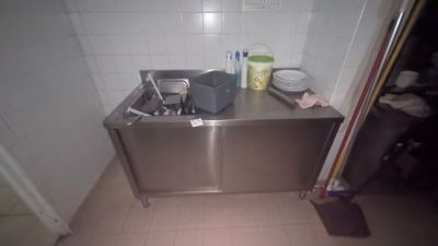un évier dans un coin de la cuisine, avec une poubelle posée sur le plan de travail
