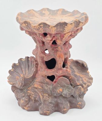 un vase rose troué posé sur une surface blanche