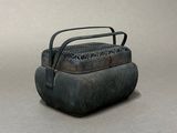 an old metal box with a handle on a gray surface
