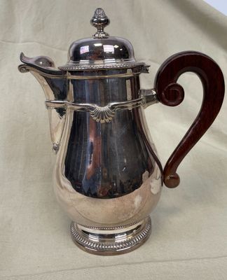une cafetière en argent avec un manche en bois sur une table