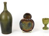 three vases and a bottle on a white surface