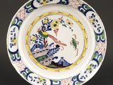 un gros plan d'une assiette décorée d'un oiseau et de fleurs