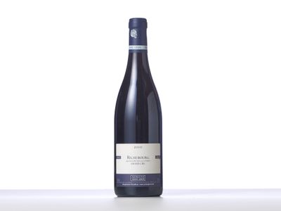 a bottle of wine sitting on top of a table next to a white wall
