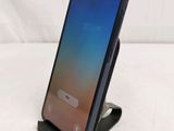 a close up of a cell phone on a stand on a white surface