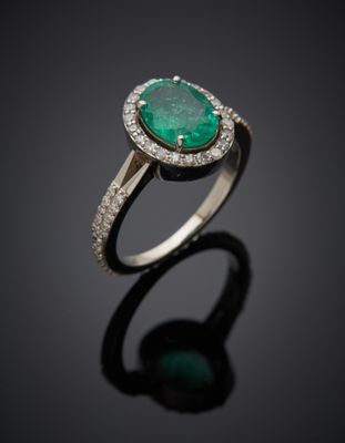 an emerald and diamond ring on a black surface