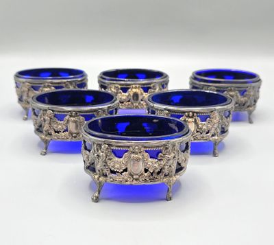 six blue glass bowls with silver decorations on them on a white surface