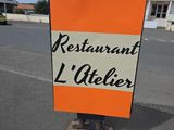 une enseigne indiquant « Restaurant L'Atelier » au bord de la route