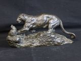 bronze statue of a cat and a cat laying on a rock
