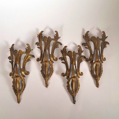 trois appliques dorées sur un mur blanc, avec un fond blanc