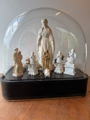 a statue of a woman surrounded by figurines under a glass dome