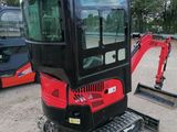 a close up of a red and black mini excavator parked in a parking lot