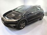 the black honda civic is parked in a white room