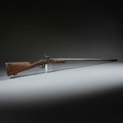un vieux fusil posé sur un socle, sur fond noir