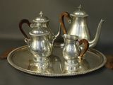 a silver tea set on a silver tray with a wooden handle