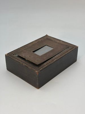 une vieille boîte en bois dotée d'une vitre, posée sur une surface blanche