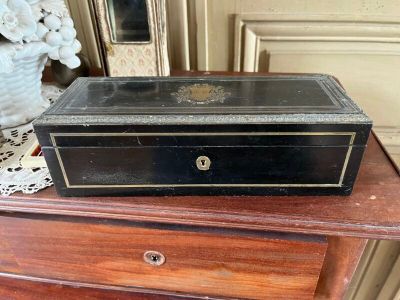 une petite boîte noire posée sur une commode en bois