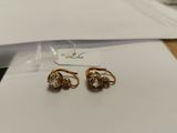 two pairs of gold and diamond earrings sitting on top of a piece of paper