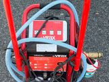 une borne d'incendie rouge posée au sol, à laquelle est raccordé un tuyau