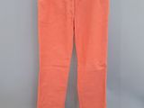 un pantalon orange suspendu à un cintre devant un mur gris