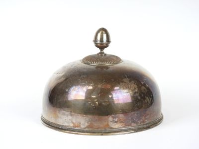 une clochette en argent posée sur une table blanche