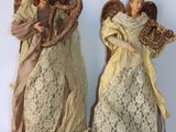 Deux figurines d'anges sont placées l'une à côté de l'autre sur une surface blanche
