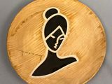 une assiette en bois sur laquelle est représentée une femme