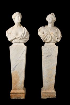 two white marble busturines of women on pedestals against a black background